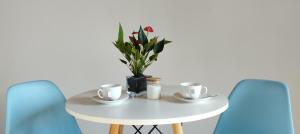a white table with two cups and a vase with flowers at Conforto e Privacidade no Roteiro do Vinho in São Roque