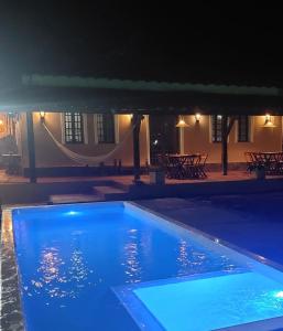 een zwembad 's nachts met een hangmat op de achtergrond bij Pousada Casa Bella in Itaberaba