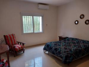 a bedroom with a bed and a chair and a window at Duplex Yrigoyen B in San Juan