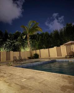 a swimming pool with a fence and a palm tree at منتجع هوانا in Salalah