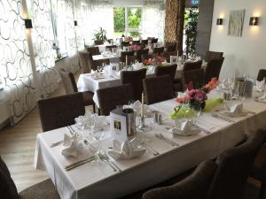 un restaurante con mesas blancas y sillas con flores. en Hotel Sachsenross, en Nörten-Hardenberg