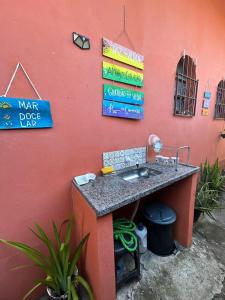 ein Waschbecken an der Seite einer roten Wand mit Schildern in der Unterkunft Hospedaria Canto Ubuntu Kitnet in Caraguatatuba