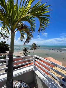 un palmier à côté d'une plage donnant sur l'océan dans l'établissement Apartamento Beira Mar centro Pipa com Piscina vista mar completo, à Pipa