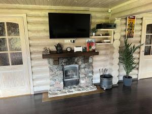 a living room with a stone fireplace with a flat screen tv at Druviņas - Peaceful Cabin by the Lake in Limbaži