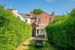 un patio con mesa y sillas frente a un seto en Host & Stay - Somerset Road House, en Birmingham