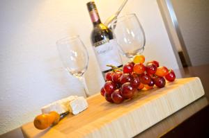 a bunch of grapes and cheese on a cutting board with wine glasses at Centro Motel in Calgary