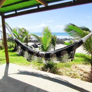 a hammock on a beach with the ocean at Céu da Vida Eco Cabana in Pipa