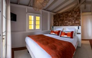um quarto com uma cama grande com almofadas laranja e branca em La Suite Villa em Les Trois-Îlets
