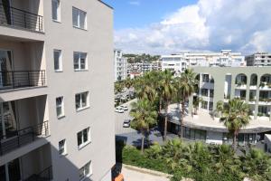 an apartment building with palm trees and a parking lot at Merxhan`S Apartment in Golem