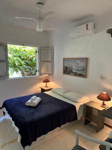 ein Schlafzimmer mit einem Bett mit zwei Lampen und einem Fenster in der Unterkunft Vila dos Tangarás, Casa 1 Praia, a 30m do mar in Toque Toque Grande