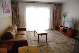 a living room with a couch and a table and a television at Energy Motor Lodge Papamoa in Tauranga