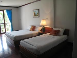 two beds in a hotel room with a lamp at Malai-Asia Resort in Thap Sakae