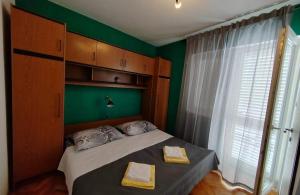 a bedroom with a bed with green walls and a window at Apartments with parking space Mundanije, Rab - 23299 in Rab