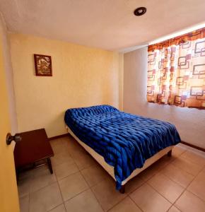 1 dormitorio con 1 cama con edredón azul y ventana en Casa Pachuca hidalgo, en Colonia de Venado
