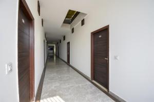 um corredor com portas de madeira e pisos em azulejo em Flagship 71214 Hotel Welcome Inn em Ludhiana
