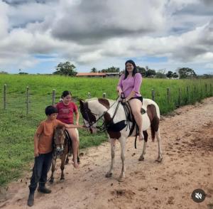 a woman sitting on a horse next to two children at Nega Joana in Araruna