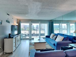 un salon avec un canapé bleu et une télévision dans l'établissement Sea Oats #409, à Fort Walton Beach
