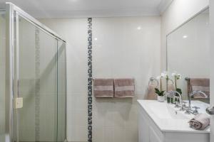 a white bathroom with a shower and a sink at Stadium Escape - A Contemporary Beachside Retreat in Wollongong +14 photos