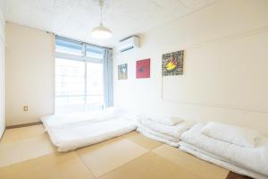 two beds in a room with a large window at Pineapple Hotel in Naha