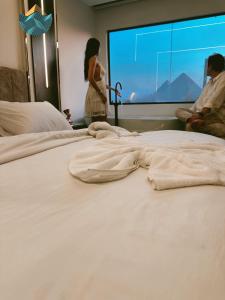 カイロにあるCrowne Pyramids view innの大きなベッドの横に立つ女性