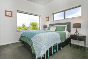 a bedroom with a large bed and two windows at Cathedral cove and Sunrise in Hahei