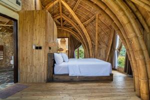 ein Schlafzimmer mit einem Bett in einem Holzzimmer in der Unterkunft Villa Grazia - Anima Eco Lodge -Ville Lussuose con Piscina Vista Mare in Selong Belanak