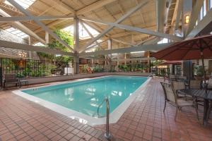 a swimming pool with a table and chairs and an umbrella at The Academy Hotel Colorado Springs in Colorado Springs
