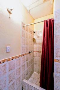 a bathroom with a shower with a red curtain at Hostal La Suite in Sangolquí