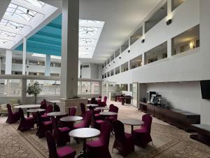 a cafeteria with tables and purple chairs in a building at Bedford Plaza Hotel - Boston in Bedford