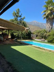 a backyard with a swimming pool with a straw roof at CASA DE CAMPO EN Aculeo in Paine