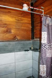 a bathroom with a shower curtain and wooden walls at Cabaña Ave Del Paraiso in Cartago