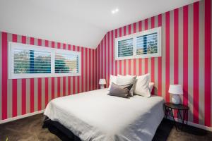 a bedroom with a red striped wall with a bed and two windows at Beacon Point Retreat by Sotheby's Luxury Rental Homes in Wanaka +17 photos