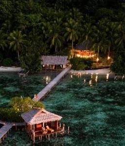 une île avec un complexe dans l'eau la nuit dans l'établissement Nyande Raja Ampat, à Pulau Mansuar