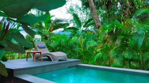 a chair and a table next to a swimming pool at Alina Farm Resort- Two Bedroom Villa in Manolo Fortich
