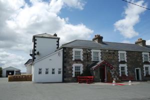 un antiguo edificio de piedra con un banco rojo delante de él en Jacks' Coastguard Cottage Vacation home, en Glenbeigh