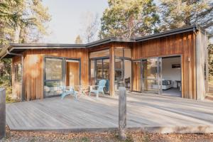 a wooden house with a deck and glass doors at Lake Tekapo Cottages in Lake Tekapo