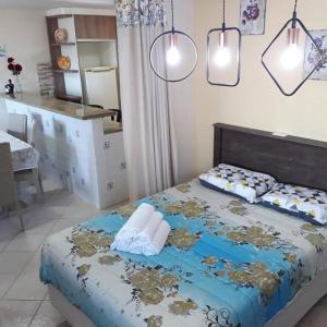 a bedroom with a bed and a kitchen with lights at Mansão Ouro Verde Beira Mar in Piçarras