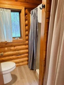 a bathroom with a toilet and a window in a log cabin at Cozy Cabin on Wooded Property in Wasilla