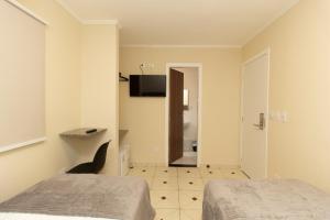 a room with two beds and a television on the wall at Hotel Villa Jequitibá in Sao Paulo