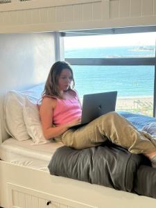 una mujer sentada en una cama con un portátil en Arabian Nights Beach Hostel, en Dubái