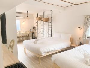 a bedroom with two beds and a dining room with a table at シャトーひらぎし in Sapporo