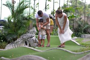 a woman and a man and a child playing golf at Anantasila Beach Resort Hua Hin in Hua Hin