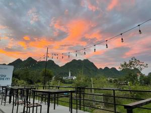 a group of tables and chairs in front of a sunset at Jungle Boss Homestay in Phong Nha
