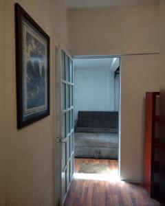 eine offene Tür zu einem Wohnzimmer mit einem Sofa in der Unterkunft Amplio y cómodo departamento in Mexiko-Stadt