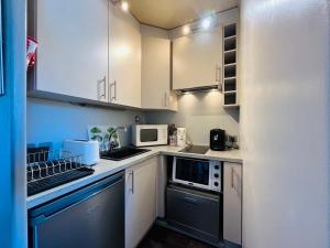eine kleine Küche mit weißen Schränken und Geräten in der Unterkunft Appartement au Mont-Dore - 2 pièces, 34m², loggia et parking, proche centre et Thermes - FR-1-608-257 in Mont-Dore