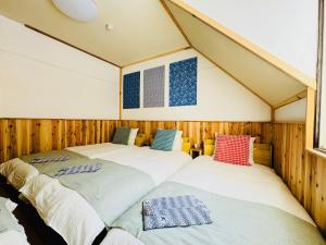 two beds in a room with wooden walls at Yama Lodge Madarao in Madarao Kogen