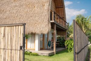 a house with a thatched roof and a gate at Makai Medewi in Airsatang