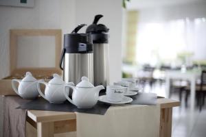 a coffee machine sitting on a table with cups and saucers at Hotel Asslar in Aßlar
