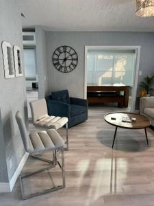 een woonkamer met een bank, een tafel en een klok bij The Little Blue House Kenwood Ping Pong Hockey Family in St Petersburg