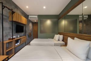 ein Hotelzimmer mit zwei Betten und einem Fernseher in der Unterkunft Rimbun Canggu Hotel in Canggu